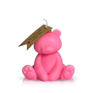 The Teddy Bear Pink Baby Candle is crafted from natural wax, shaped like a teddy bear, and includes a brown wick tag with handwritten text and a small red heart.