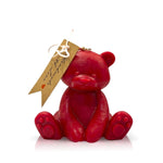 The Teddy Bear Red Baby Candle is a natural wax candle shaped like a red teddy bear, with a gold string and brown tag on its ear—an ideal Valentine’s Day gift, shown on a white background.