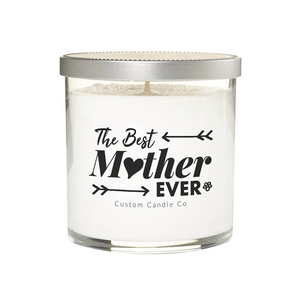 The Best Mother Ever White Glass Candle: a white soy candle in a clear jar with a silver lid, labeled "The Best Mother Ever," "I Love You Mom," and "Custom Candle Co" in black text with decorative arrows.