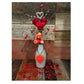 Valentine Bouquets feature red roses and heart-themed accents in a repurposed vase, with red heart ornaments on a wooden surface—a beautiful, eco-friendly Valentine’s Day gift.