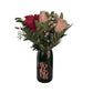 The Valentine Bouquets feature red and white roses with greenery arranged in a repurposed dark Bollinger champagne bottle for an elegant, eco-friendly touch against a white background.