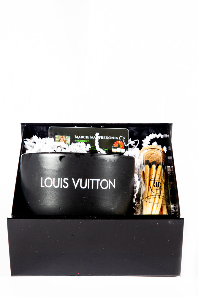 The LV Candle Designer Gift Set features a black Louis Vuitton candle, a jar of matches, and a gift card in a black box with white shredded paper—an elegant custom candle gift for any occasion.