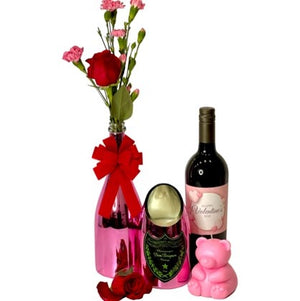 The Valentines Luxourious Gift Set – Pink Shiney set includes a pink shiny vase with flowers and red bow, a bottle of red wine, heart-shaped box, pink teddy bear, and a red rose arranged beautifully together.