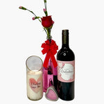 The Valentines Luxourious Gift Set – Pink/Clear Shiney set includes a pink vase with a red rose, a "Happy Valentine's Day" wine bottle, a champagne-scented "I Fucking Love You" candle, and a heart-shaped tin on a white background.