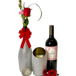 The Valentines Luxourious Gift Set – Silver Diamond set features a "Happy Valentine's Day" wine, a single red rose in a silver diamond vase, a lit champagne candle, and a small heart-shaped box, elegantly arranged together.