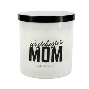 The Westchester Mom White Glass Candle is a hand-poured soy candle with a black lid, labeled "Westchester Mom" and "Custom Candle Co." It’s a thoughtful gift or a cozy addition to any home.