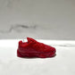 The Y500 – Red Sneaker Candle – Small (On Backorder), hand poured from natural wax, is displayed on a white surface against a blurred marble-patterned background.