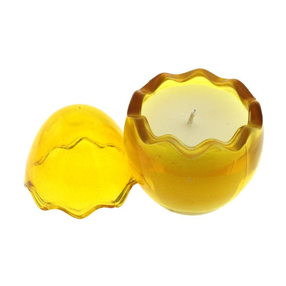 The Yellow Glass Easter Egg is a round, yellow, translucent candle holder with a wavy edge and matching lid that holds a white natural wax candle, adding elegance and a subtle peeps fragrance to your space.