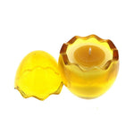 The Yellow Glass Easter Egg w/ Yoke is a glass candle holder shaped like a cracked egg, featuring a natural wax candle inside with the top half placed beside it—perfect for displaying your favorite peeps fragrance.