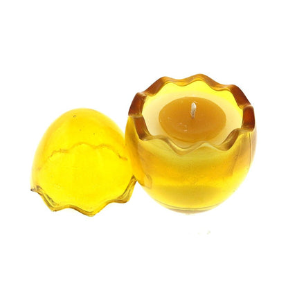 The Yellow Glass Easter Egg w/ Yoke is a glass candle holder shaped like a cracked egg, featuring a natural wax candle inside with the top half placed beside it—perfect for displaying your favorite peeps fragrance.