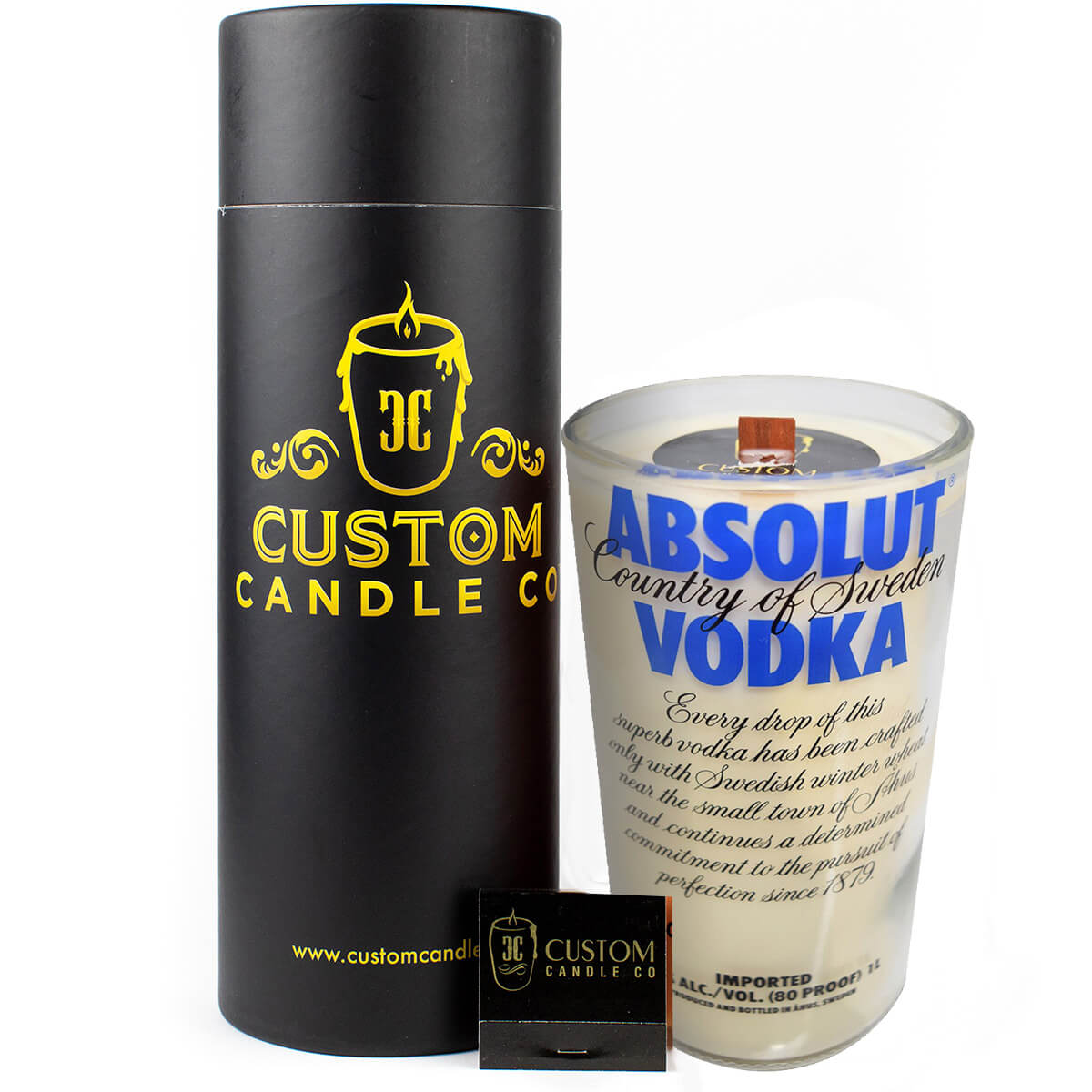The Recycled Blue Letter Vodka Candle, made from a repurposed Absolut Vodka bottle, is displayed with a black cylindrical Custom Candle Co. box and a matching small black matchbox.