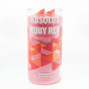The Recycled Ruby Vodka Candle is a clear glass upcycled from Absolut Ruby Red vodka branding with geometric red and orange shapes, hand poured with pink natural soy wax.