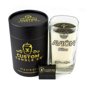 The Recycled Mexican-Style Silver Tequila Candle comes in a soy wax Avión Silver Tequila bottle glass with a black cylinder box and branded matchbox—an eco-friendly recycled gift perfect for tequila lovers.