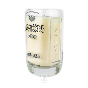 A Recycled Mexican-Style Silver Tequila Candle, made from a clear glass tequila bottle branded "Avión Silver Tequila," holds a light-colored wax and sits against a plain white background—a creative take on tequila bottle candles.
