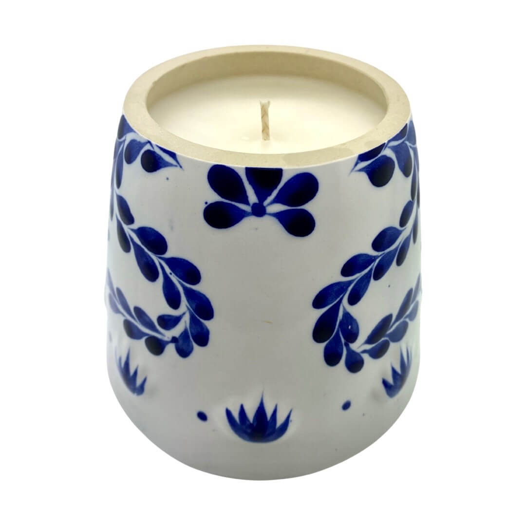 The Recycled Azul Tequila Candle is a hand-poured soy candle in a ceramic holder with blue floral patterns, showcased on a plain white background.