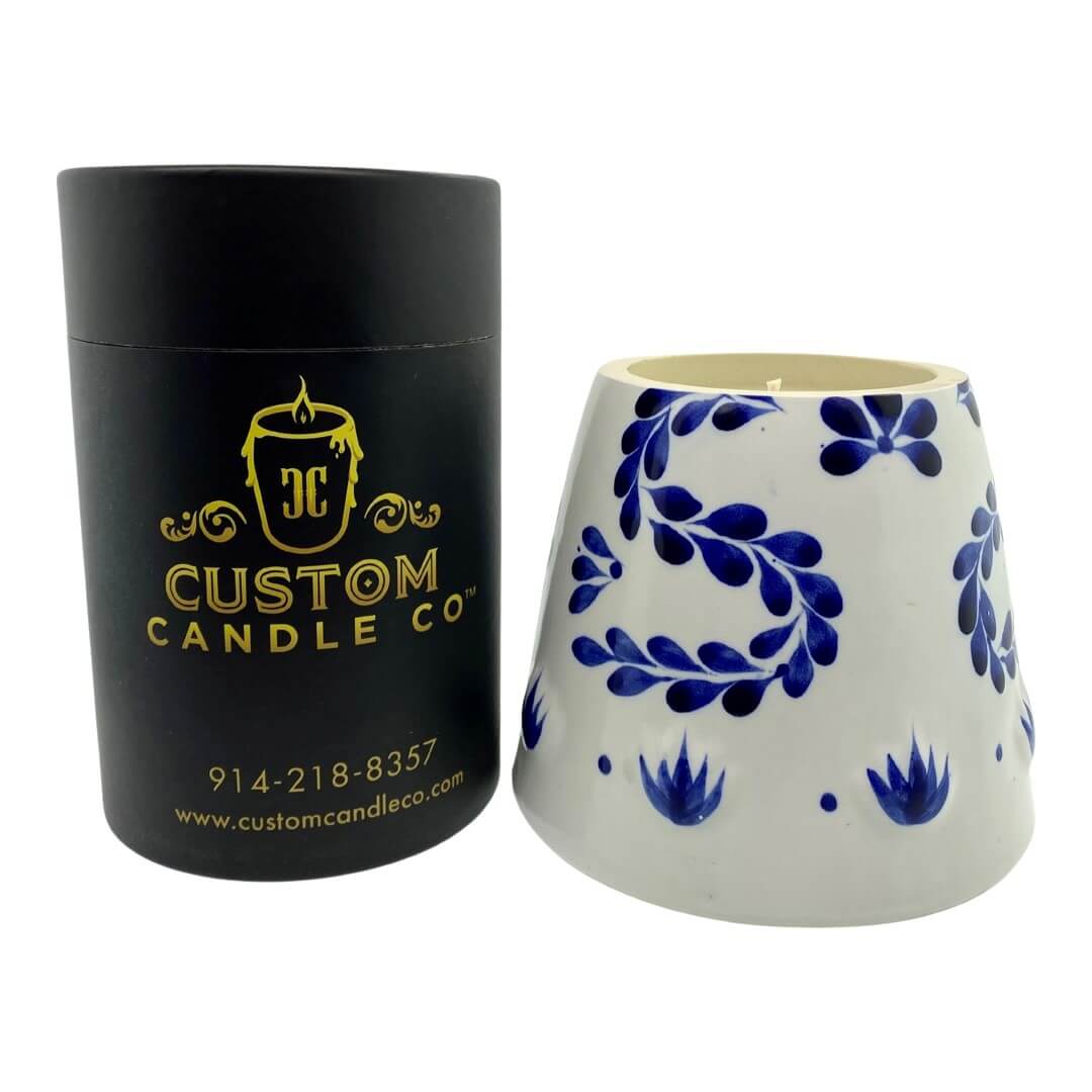 A black "Recycled Azul Tequila Candle" stands beside a white holder with blue floral patterns, showcasing a hand-poured, cruelty-free soy candle that's both sustainable and elegant.
