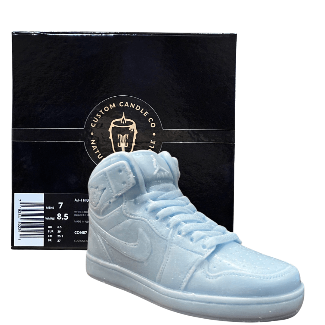 The AJ-1 Baby Blue Sneaker Candle – Large (On Backorder), hand poured with a Black Ice fragrance, is shown in front of a black "Custom Candle Co." box featuring product details on the side.