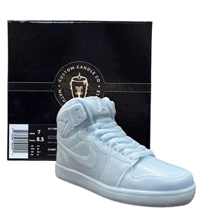 The AJ-1 Baby Blue Sneaker Candle – Large (On Backorder), hand poured with a Black Ice fragrance, is shown in front of a black "Custom Candle Co." box featuring product details on the side.