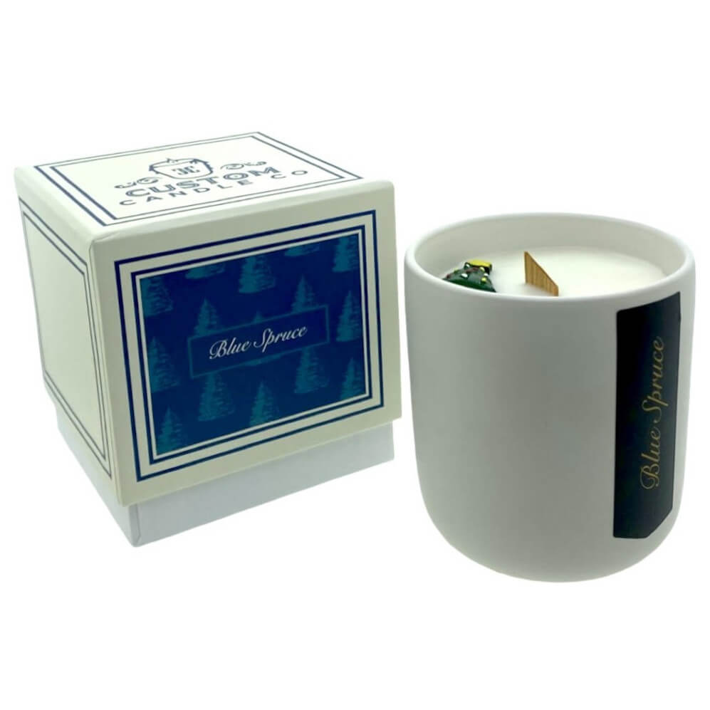 The Holiday Scented Boxed Candle – Blue Spruce Scent features a white soy wax candle in a white container beside its coordinating blue and white box, delivering a festive holiday fragrance.