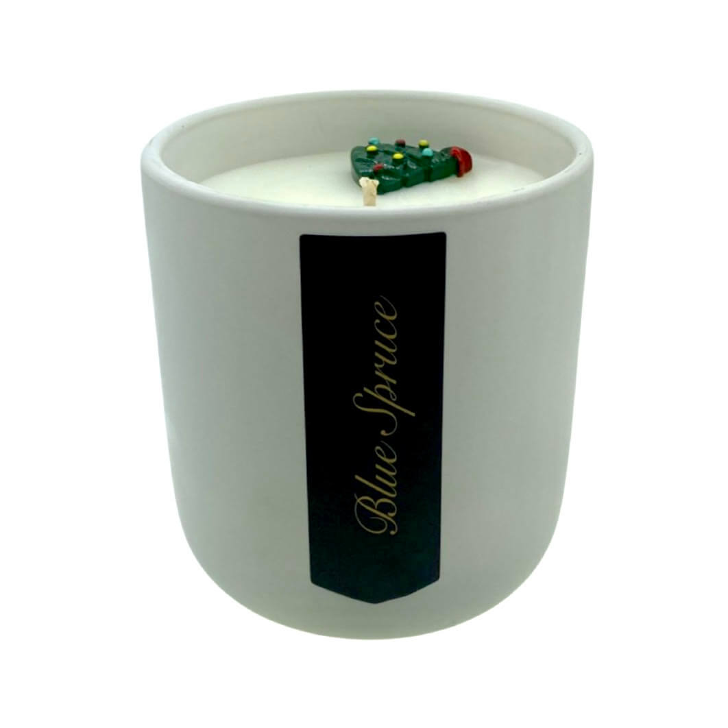The Holiday Scented Boxed Candle – Blue Spruce Scent features white soy wax in a labeled jar with a decorative Christmas tree, filling your space with a festive holiday aroma.
