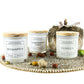 Three glass candles—Eucalyptus, LEMONGRASS SAGE Relaxing Aromatherapy Candle 11oz, and Vanilla—sit on a decorative tray with small artificial pumpkins and a textured ornament in the background for a calming candle display.