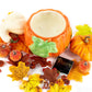 The Ceramic Large Leaf Pumpkin Candle, paired with artificial autumn leaves, small pumpkins, berries, and a Custom Candle Co. matchbox, sets a cozy scene—ideal for highlighting pumpkin spice or your favorite soy candle fragrance.