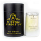 A black cylindrical "Custom Candle Co." box stands beside a white glass labeled "Product of France," showcasing our Recycled Vodka Candle – Multi-color, crafted from vodka that is distilled five times.
