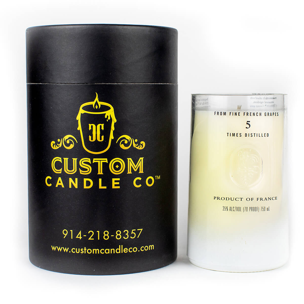 A black cylindrical "Custom Candle Co." box stands beside a white glass labeled "Product of France," showcasing our Recycled Vodka Candle – Multi-color, crafted from vodka that is distilled five times.