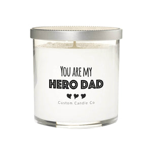 The “You are My Hero Dad” candle is a white natural soy candle in a clear glass jar with a silver lid—a thoughtful custom gift for dad featuring “You are my hero dad” on the label and made by Custom Candle Co.