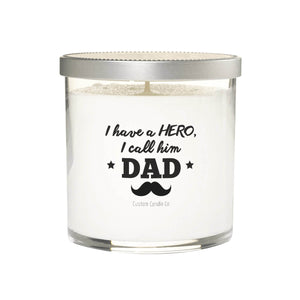 The "I Have a hero, I Called him Dad" candle is a natural soy white candle in a glass jar with a silver lid, featuring a mustache and stars on the label—making it the perfect custom gift for dad.