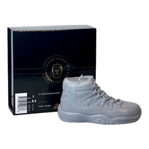 The AJ-11 Gray Hightop Sneaker Candle – Large (On Backorder), hand poured with Black Ice fragrance, sits in front of a black "Custom Candle Co." box showing product and size information.
