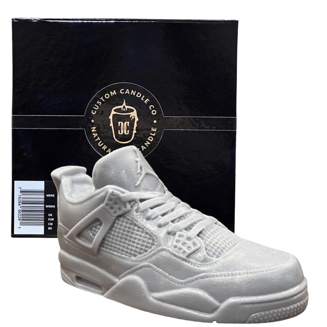 The AJ-4 Gray Sneaker Candle – XL, shaped like a gray sneaker, is shown before a black "Custom Candle Co. Natural Candle" box and features the fresh Black Ice scent; this unique hand-poured candle is currently on backorder.