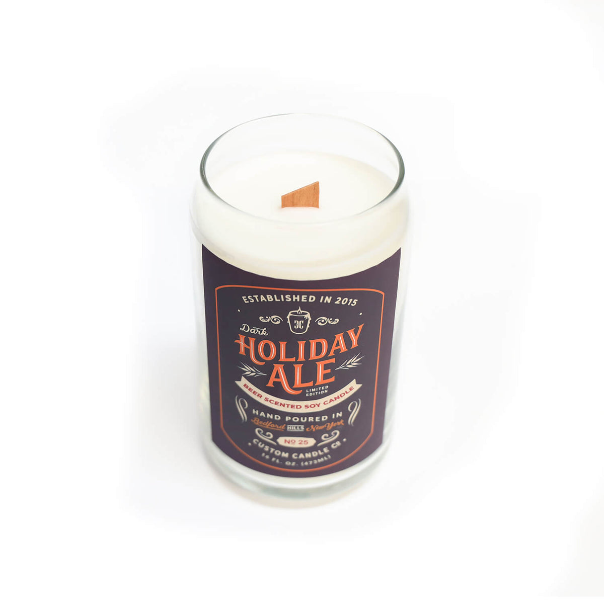 The Dark Holiday Ale Candle is a hand-poured natural soy candle in a beer can-shaped glass with a wooden wick and festive "Holiday Ale" label.