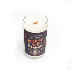 The Dark Holiday Ale Candle is a hand-poured natural soy candle in a beer can-shaped glass with a wooden wick and festive "Holiday Ale" label.