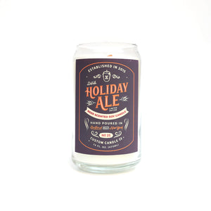 The Dark Holiday Ale Candle is a hand-poured, beer-scented candle crafted from natural soy in a clear glass, featuring a "Dark Holiday Ale" label and designed to look like a classic 12 oz beer can.