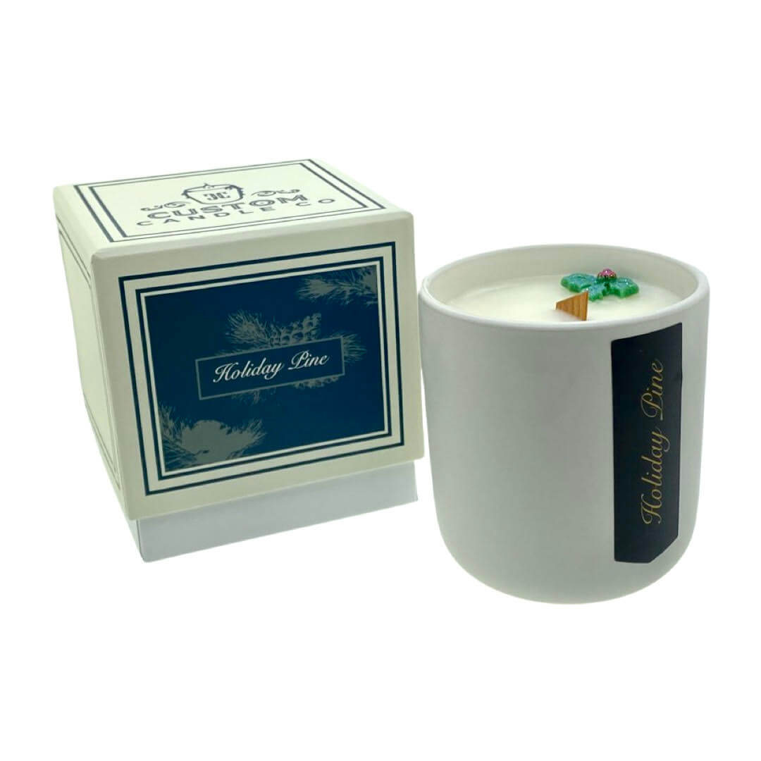 The Holiday Scented Boxed Candle – Holiday Pine Scent features a white jar with natural soy wax, a decorative element on top, and comes in a matching box.