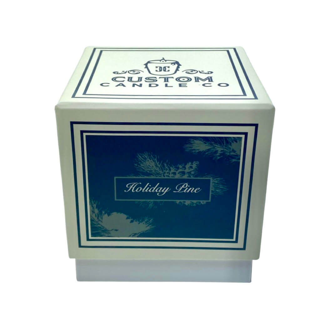 The Holiday Scented Boxed Candle – Holiday Pine Scent comes in a square box labeled "Custom Candle Co" with a blue "Holiday Pine" panel and pine branch graphics, holding a natural soy wax candle infused with holiday pine fragrance.