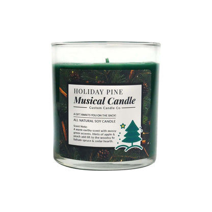 The Musical Holiday Candle – Holiday Pine is a green soy candle in a clear glass jar, featuring pine branch decorations and scent details on the front—a festive choice for fans of musical Christmas candles.