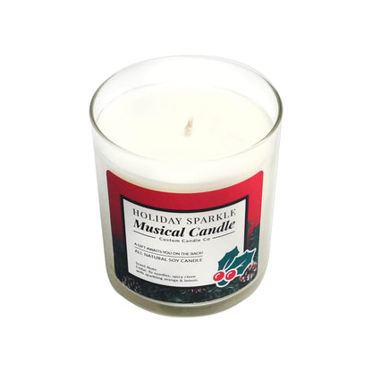 The Musical Holiday Candle – Holiday Sparkle is a white soy candle in a clear glass jar with a festive red label and holiday decorations, offering delightful music and aroma for a cheerful Christmas atmosphere.