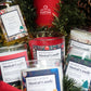 The Musical Holiday Candle – Jack Frost adds festive fragrance to your home with its seasonal scent, presented among pine branches and ornaments for a cheerful holiday display.