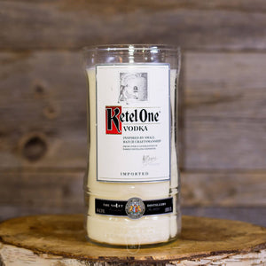 The Recycled Imported Vodka Candle features a natural soy candle in a repurposed vodka bottle with its original label, shown on a wooden surface against a rustic wood backdrop.