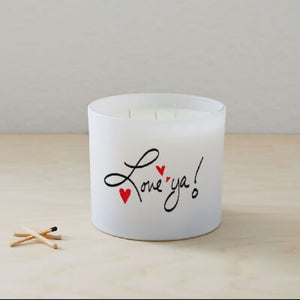 The Love ya Quote Candle (Frosted tumbler jar) is a hand-poured white soy candle with "Love ya!" and two red hearts on the glass, shown on a light wooden surface next to three wooden matches.