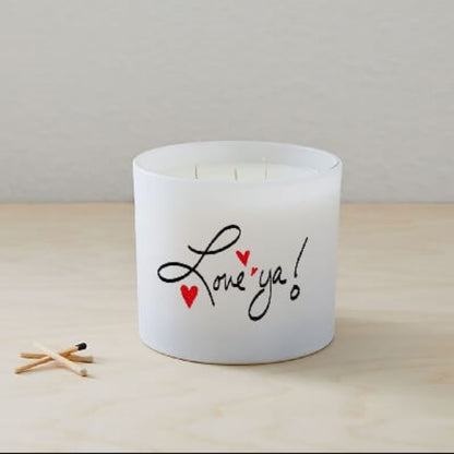 The Love ya Quote Candle (Frosted tumbler jar) is a hand-poured white soy candle with "Love ya!" and two red hearts on the glass, shown on a light wooden surface next to three wooden matches.