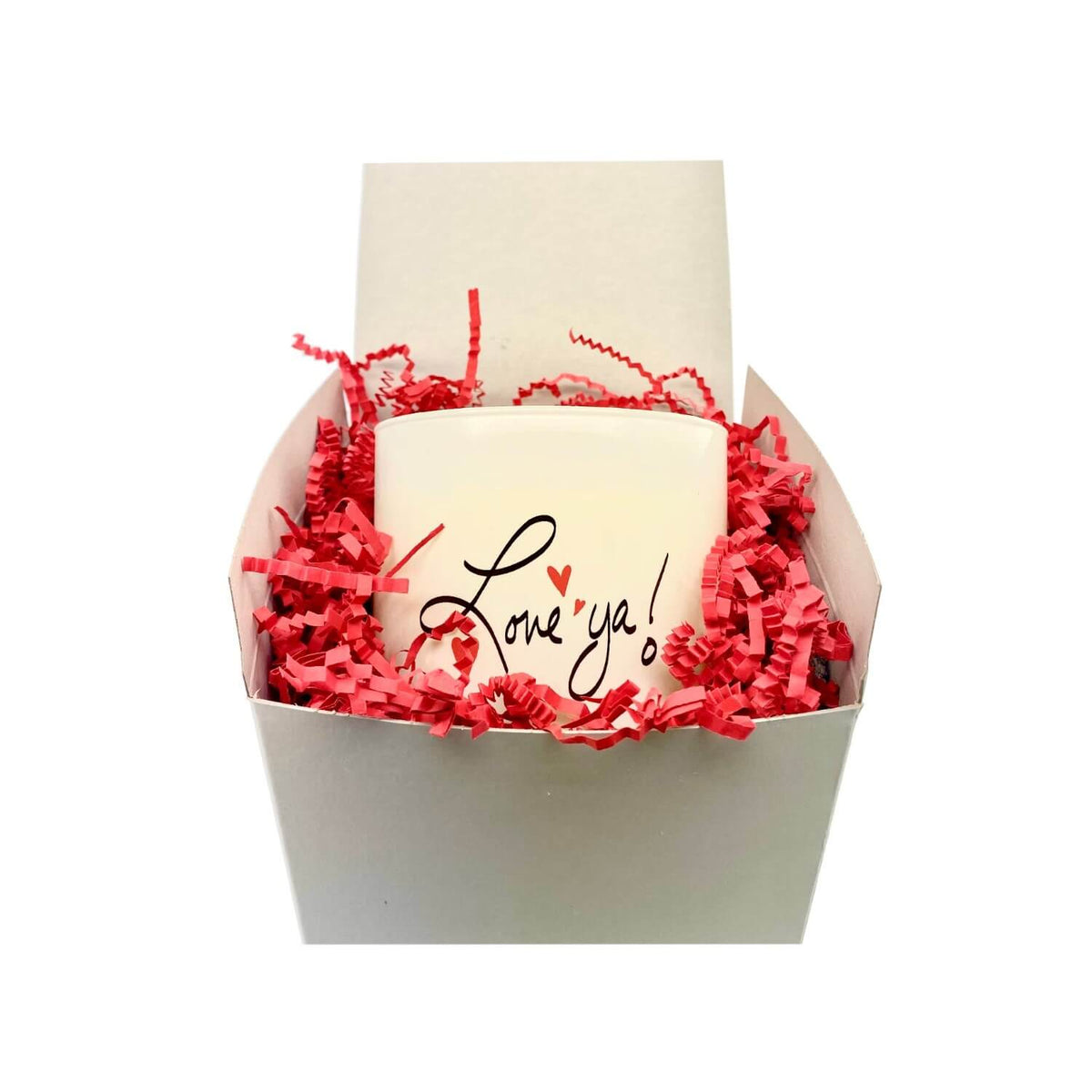 A hand poured white soy Love ya Quote Candle in a frosted tumbler jar with "Love ya!" written on it comes in a white box filled with red paper shreds.