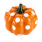The Ceramic Mini Polka Orange Pumpkin Candle features a pumpkin-shaped orange ceramic container with large white polka dots and a green stem, ideal for holding candles, displayed against a plain white background.