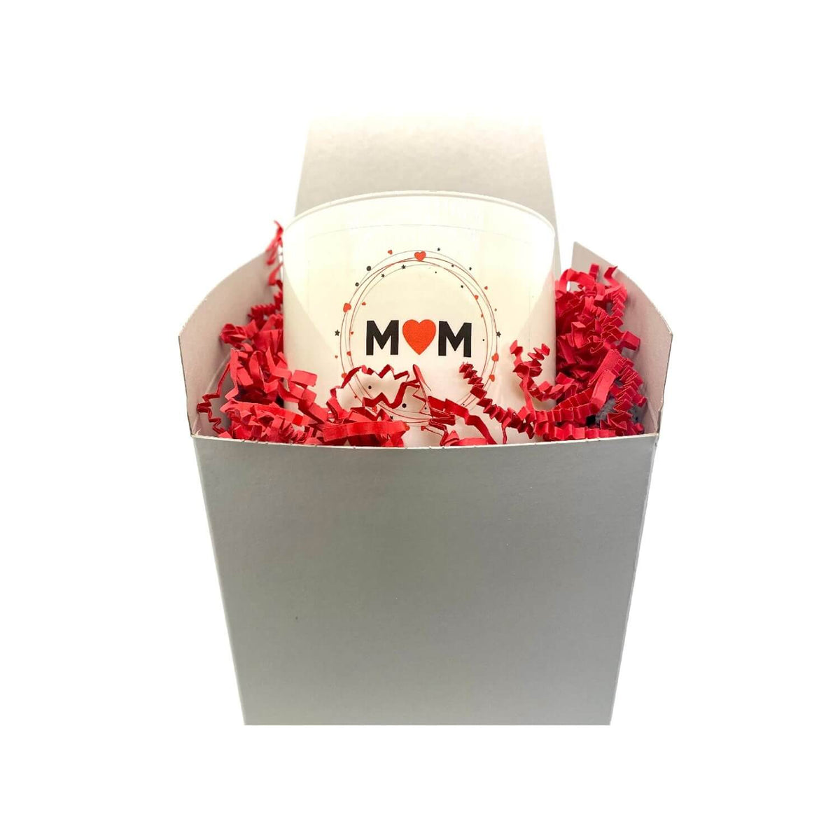 A white cup with "MOM" and a red heart sits in a white box with red shredded paper, perfect for gifting with the Mom Quote Candle in a frosted tumbler jar.