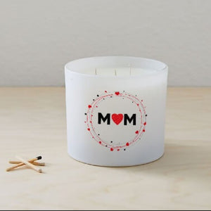 The Mom Quote Candle (Frosted tumbler jar), a hand poured soy wax candle labeled "MOM" with a red heart, sits on light wood next to three wooden matches.
