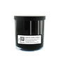 The Musical Halloween Candle – Candy Corn comes in a black glass jar with a black lid. Its label includes text, a QR code for a music playlist, and candy corn accents—ideal for unique soy candle lovers.