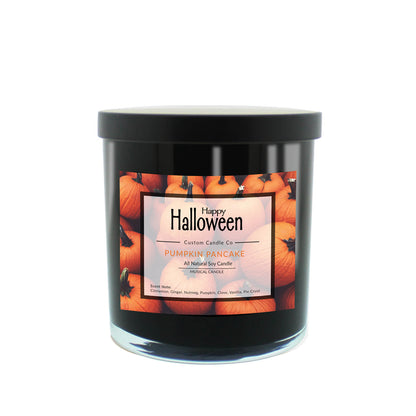A Musical Halloween Candle – Pumpkin Pancake, in a black jar with a pumpkin-themed label that says "Happy Halloween" and "Pumpkin Pancake All Natural Soy Candle.