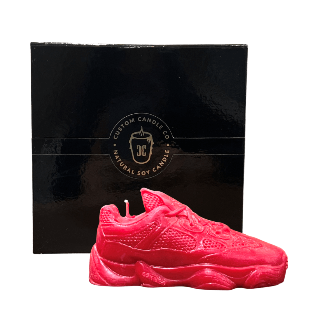 The Y500 – Red Sneaker Candle – Small (currently on backorder) is a hand-poured natural wax candle, shown in front of a black "Custom Candle Co. Natural Soy Candle" box.
